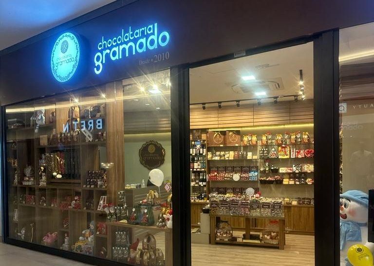 Uma fachada de loja com uma placa que diz chocolatena gramado.