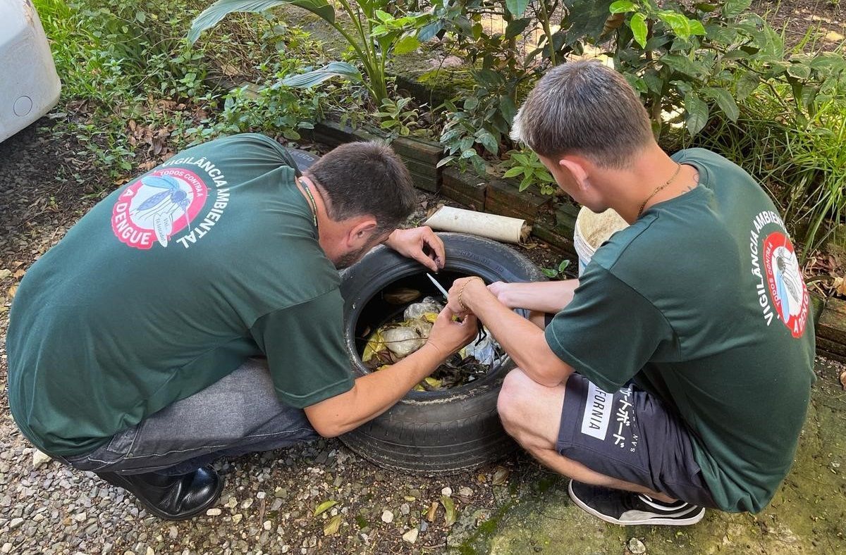 Dois homens estão ajoelhados e trabalhando em um pneu.