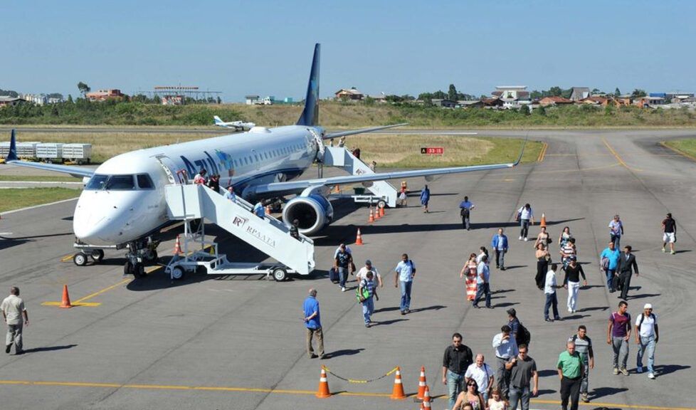 Um grupo de pessoas está caminhando em direção a um avião na pista