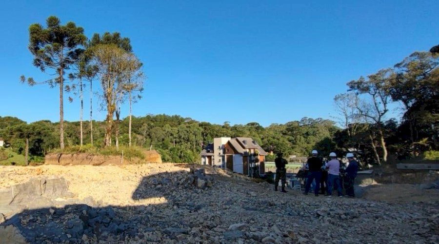 Um grupo de pessoas está em um campo de terra com árvores ao fundo.