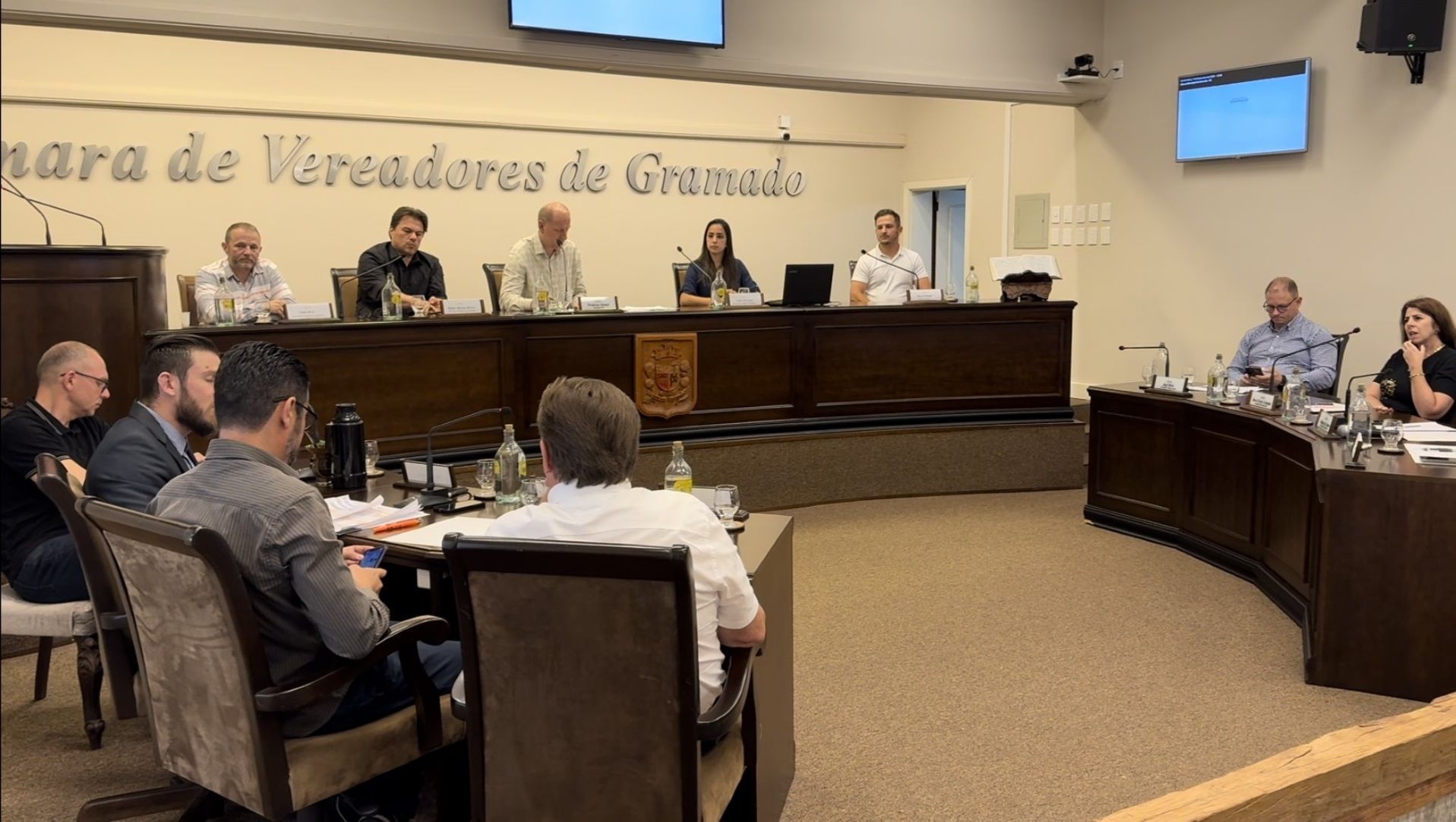 Um grupo de pessoas está sentado em mesas em uma sala de conferências.