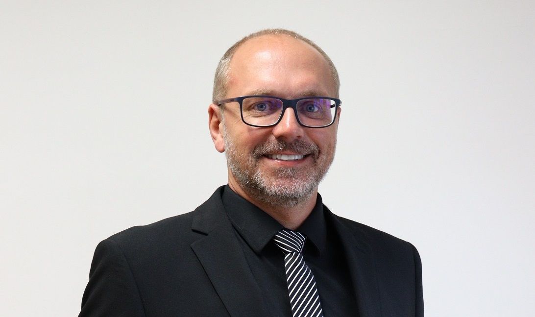 Um homem de terno e gravata está sorrindo para a câmera.