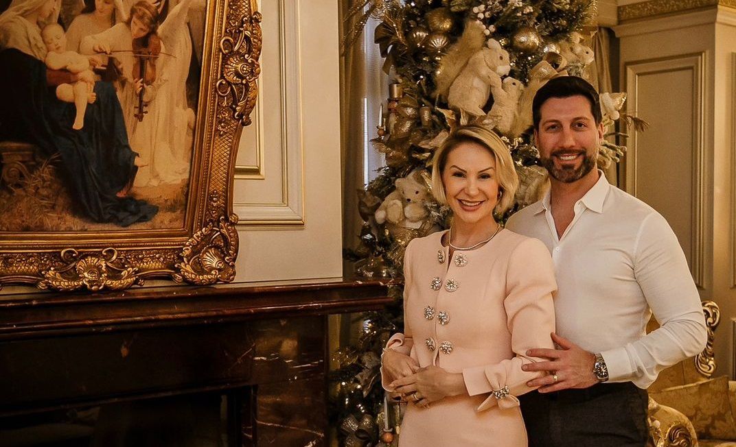 Um homem e uma mulher posam para uma foto em frente a uma árvore de natal.