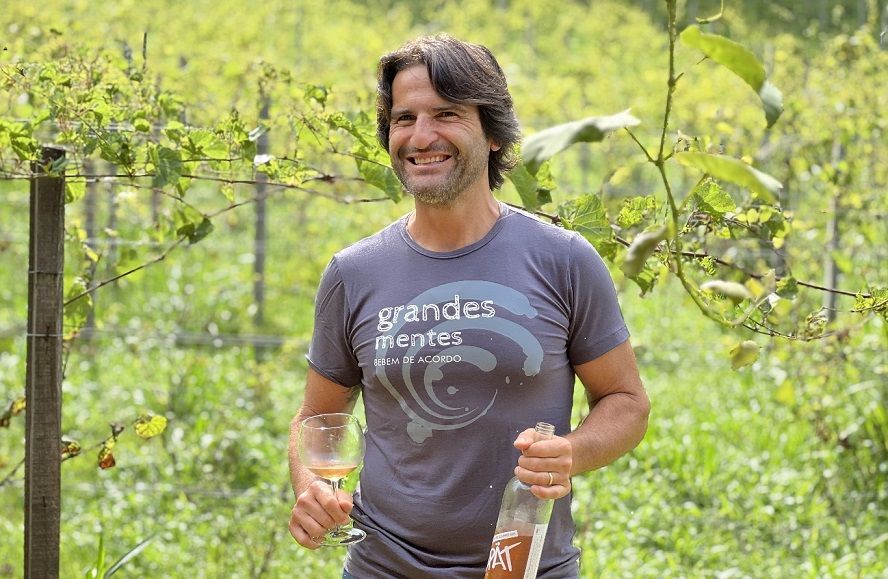 Um homem está parado em um campo segurando uma garrafa de vinho.