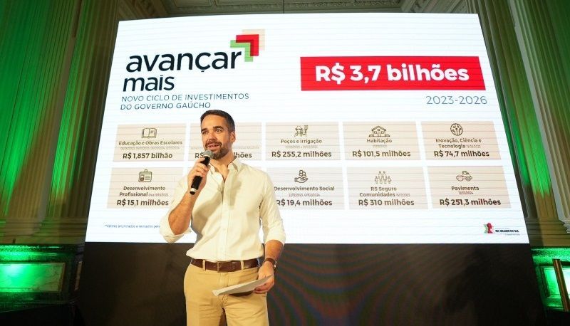 Um homem está diante de uma grande tela segurando um microfone.