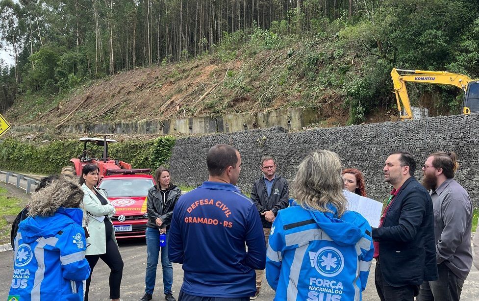 Um grupo de pessoas forma um círculo na beira de uma estrada.