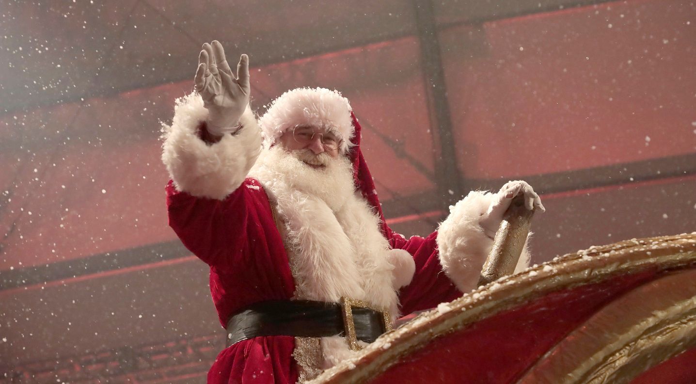 Papai Noel está acenando na parte de trás de um trenó.