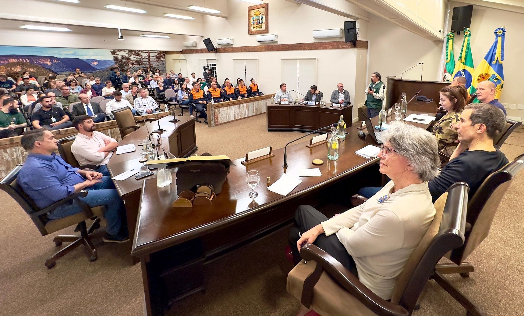 Um grupo de pessoas está sentado à mesa em uma sala de conferências.