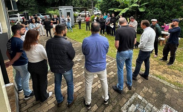 Um grupo de pessoas forma um círculo em uma calçada de tijolos.