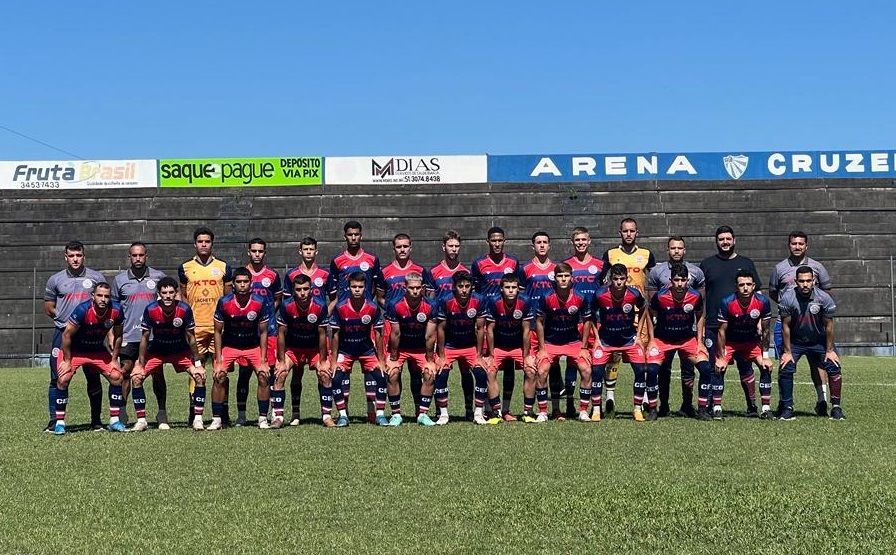 Um grupo de jogadores de futebol posa para uma foto do time em um campo.