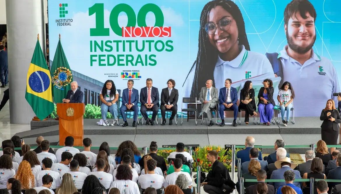Um grande grupo de pessoas está sentado em frente a um pódio.