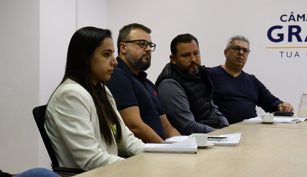 Um grupo de pessoas está sentado em uma mesa em uma reunião.