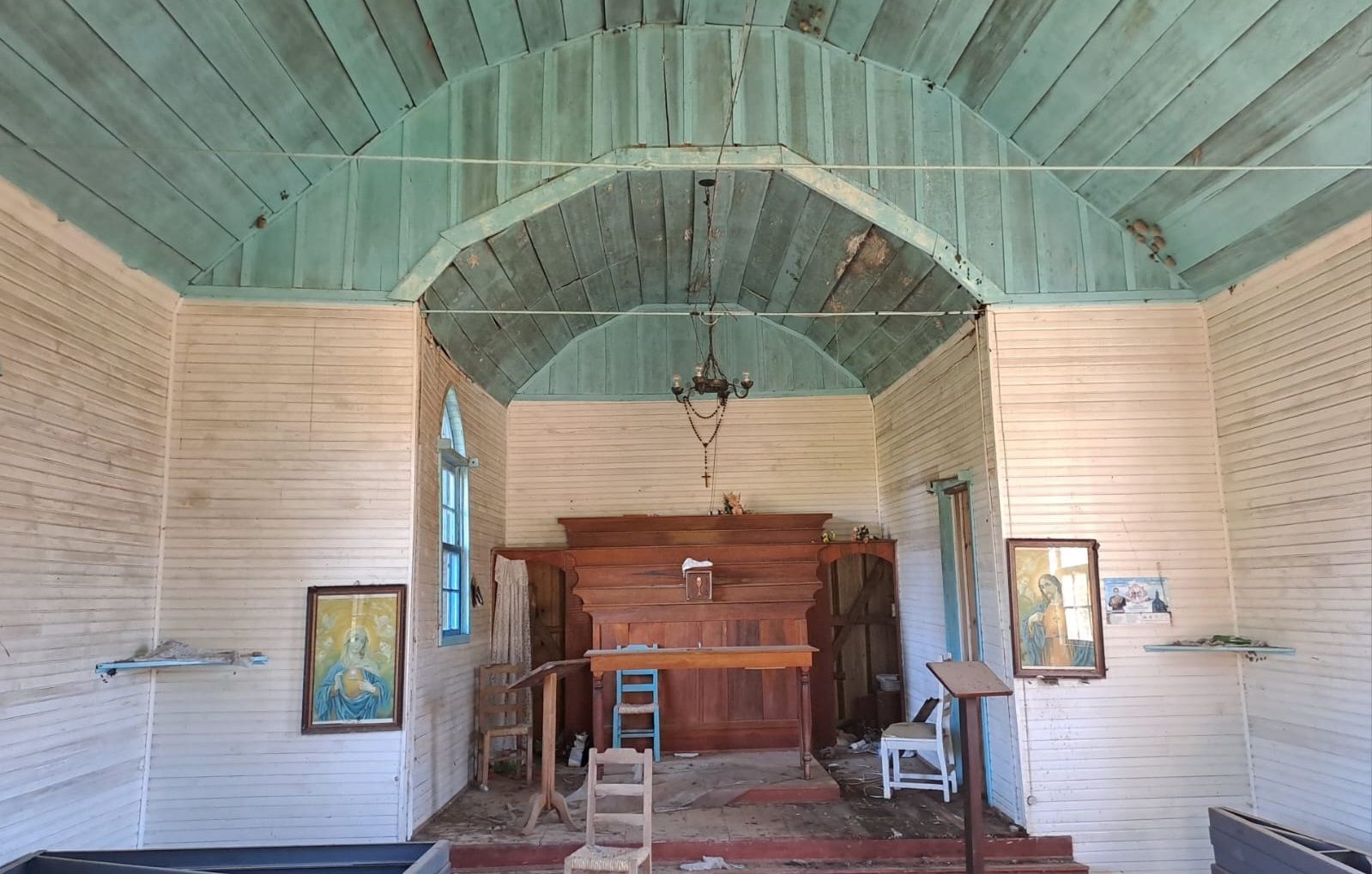 O interior de uma antiga igreja de madeira com teto verde.