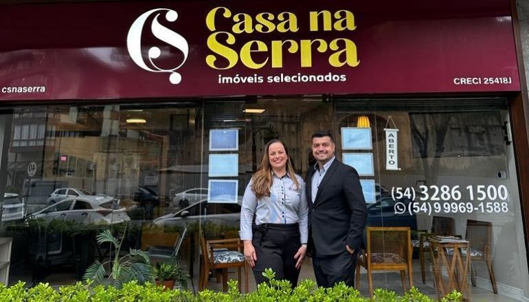Um homem e uma mulher estão em frente a um prédio que diz casa na serra