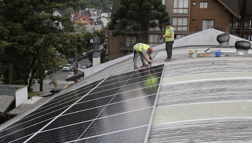 Dois homens estão trabalhando em um telhado com painéis solares