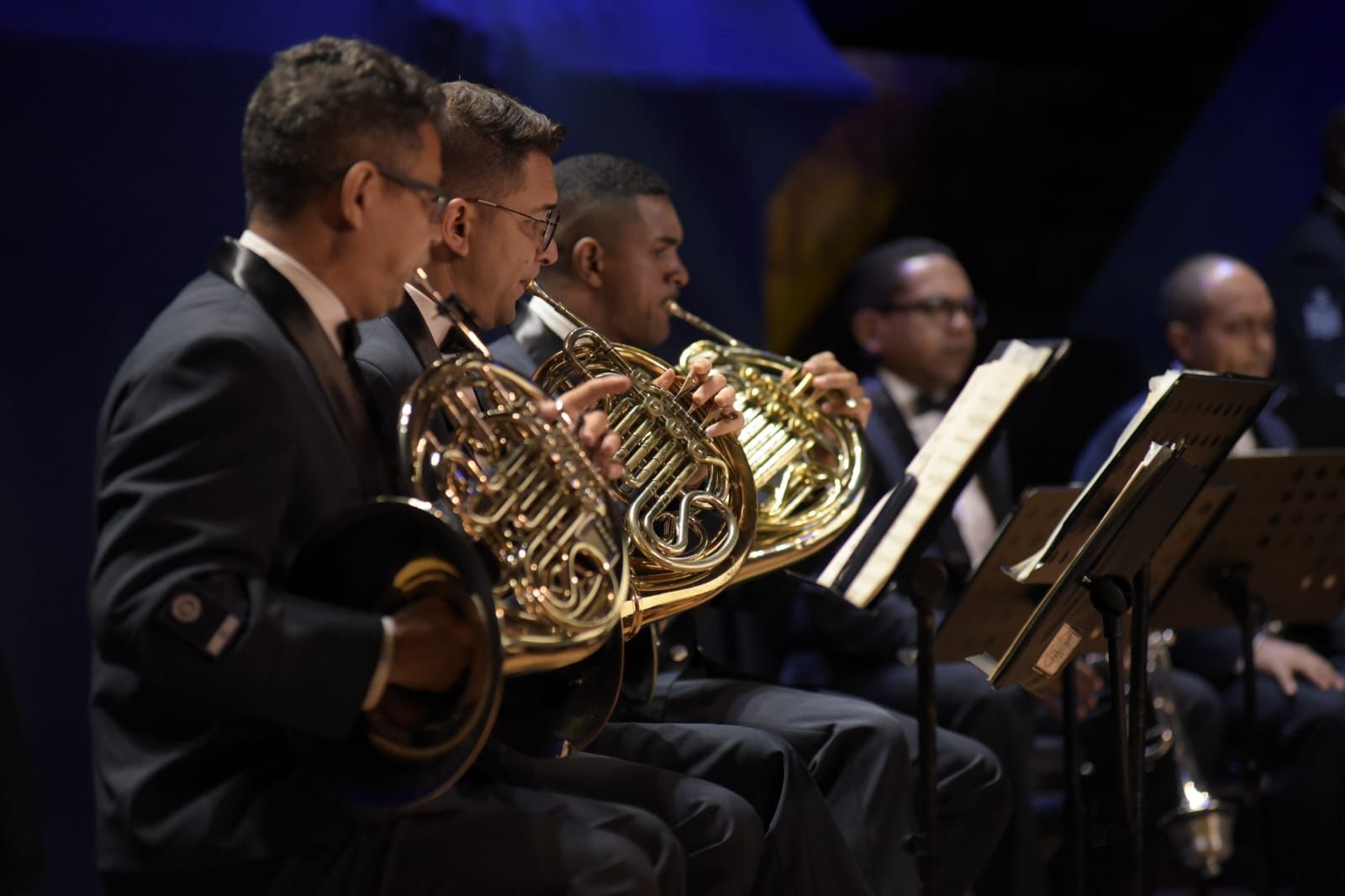 Um grupo de homens toca trompas em uma orquestra