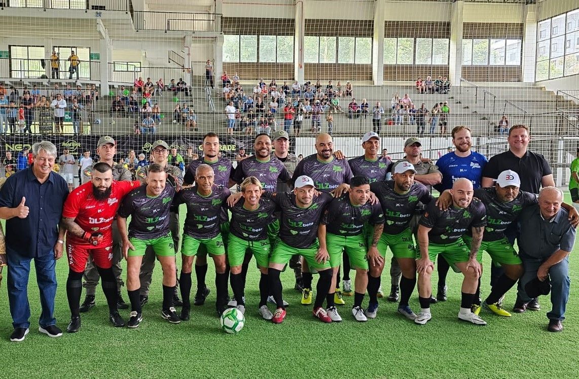 Um grupo de homens posa para uma foto em um campo de futebol.