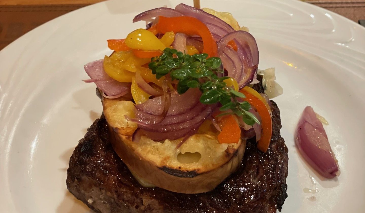 Um prato branco coberto com bife e legumes.