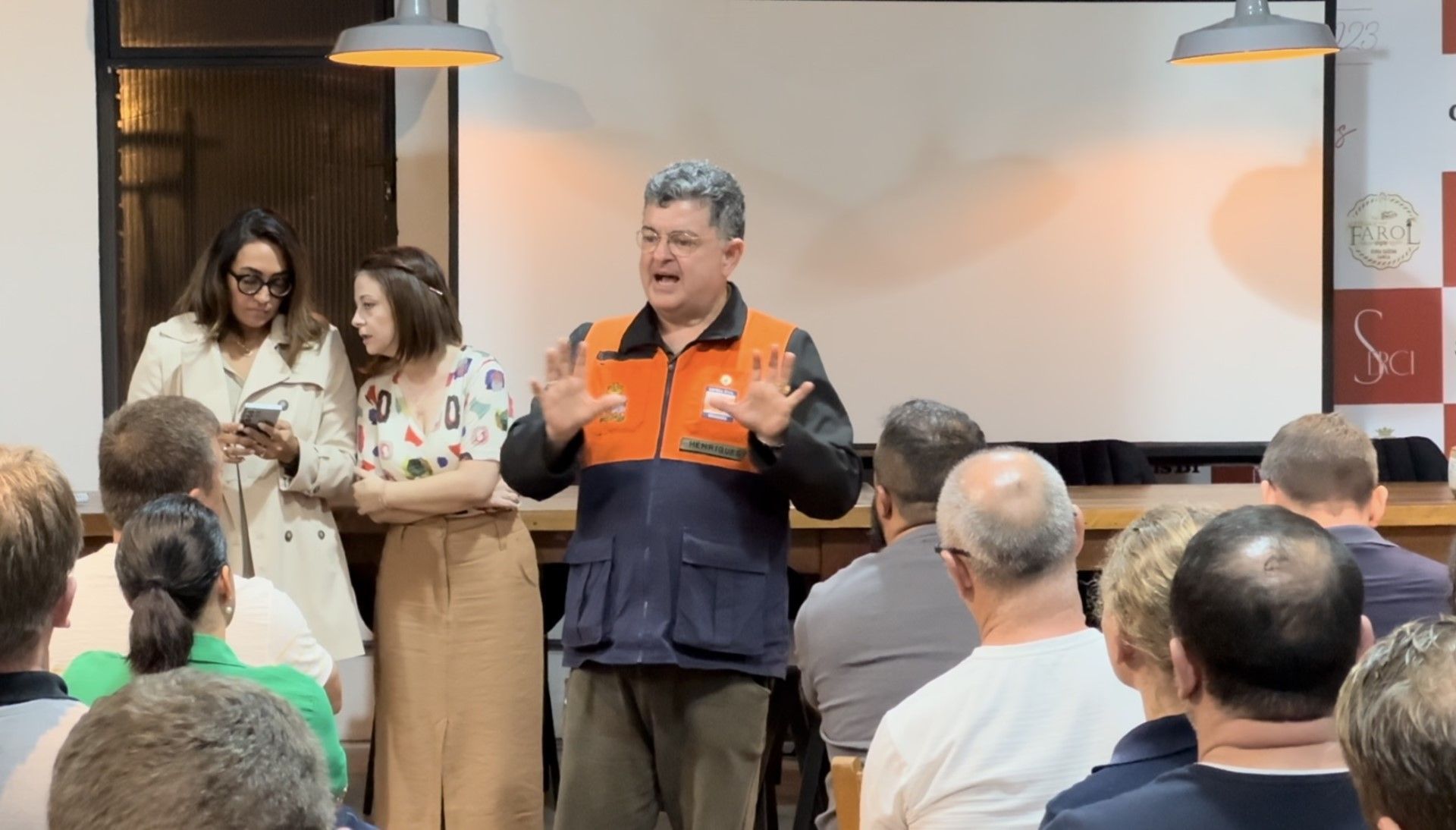 Um homem está diante de um grupo de pessoas fazendo uma apresentação.