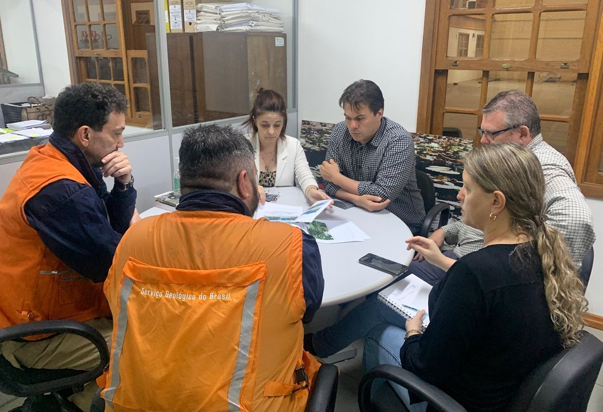 Um grupo de pessoas está sentado ao redor de uma mesa em uma reunião.