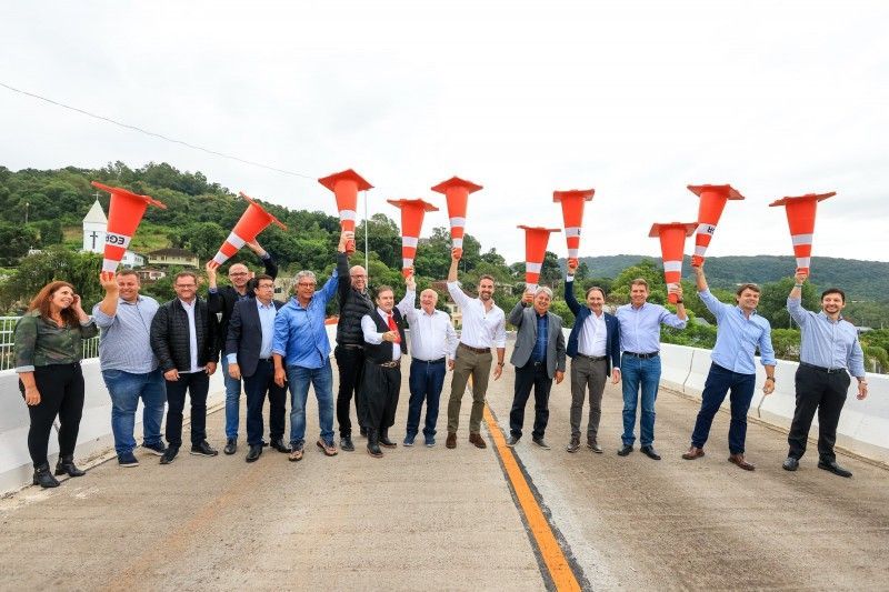 Um grupo de pessoas está em uma ponte segurando cones de trânsito.