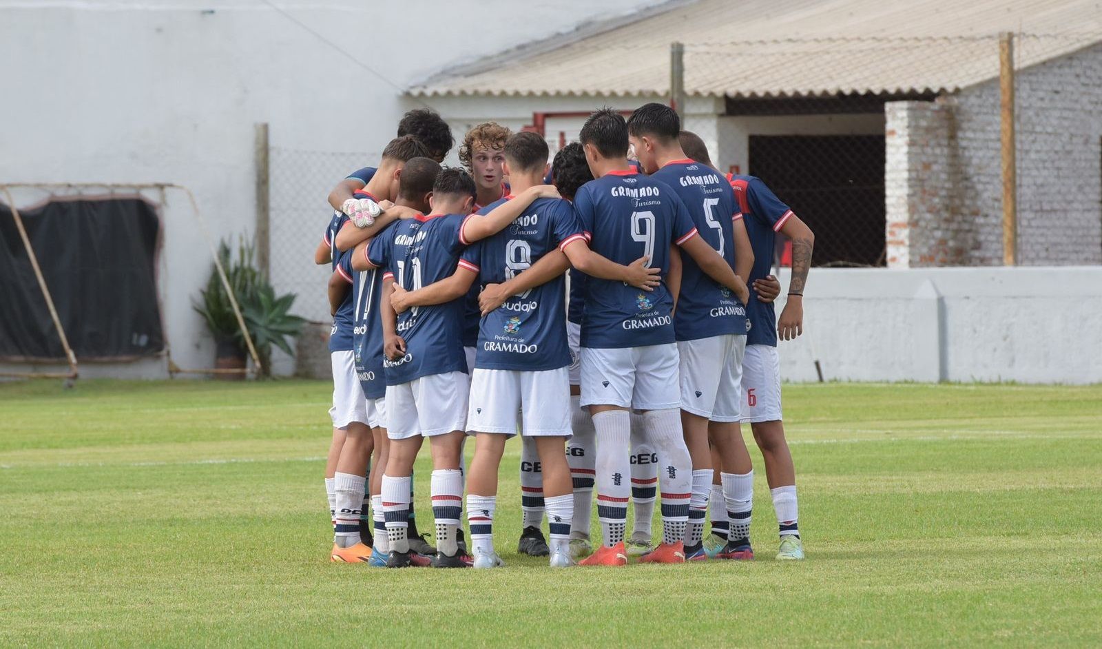 Um grupo de jogadores de futebol está amontoado em um campo.