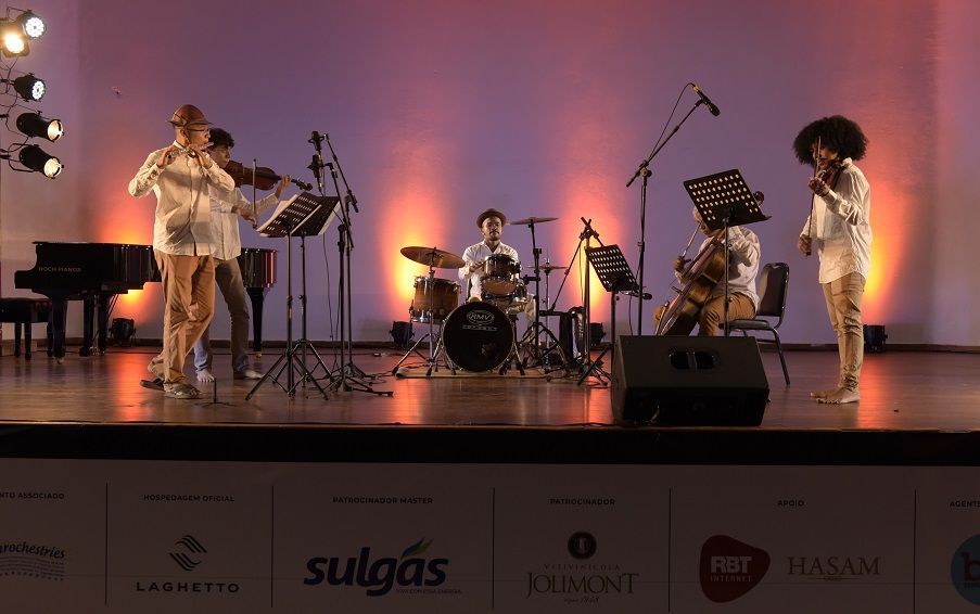 Um grupo de pessoas está em um palco tocando instrumentos.