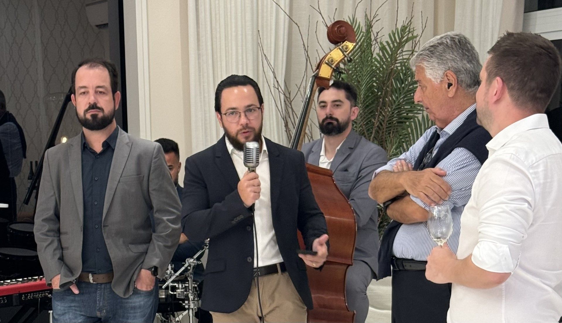 Um homem segura um microfone na frente de um grupo de homens.