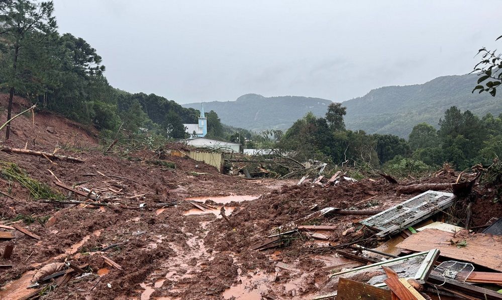 Uma estrada lamacenta com uma casa ao fundo e montanhas ao fundo.