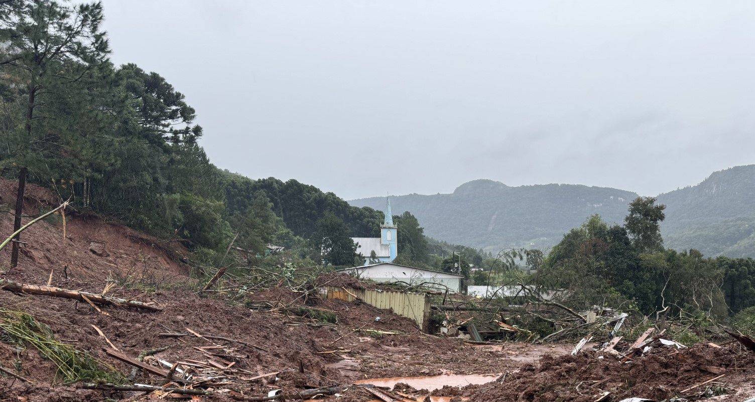 Uma estrada de terra com uma igreja ao fundo e árvores ao lado.