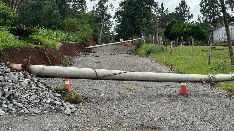 Um poste quebrado está na beira de uma estrada de cascalho.