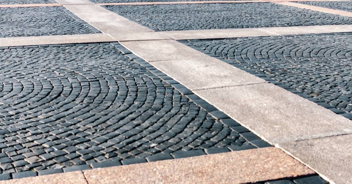 A closeup on the surface tiles of a plaza square. Small granite tiles make up a sleek square layout of the pavement.