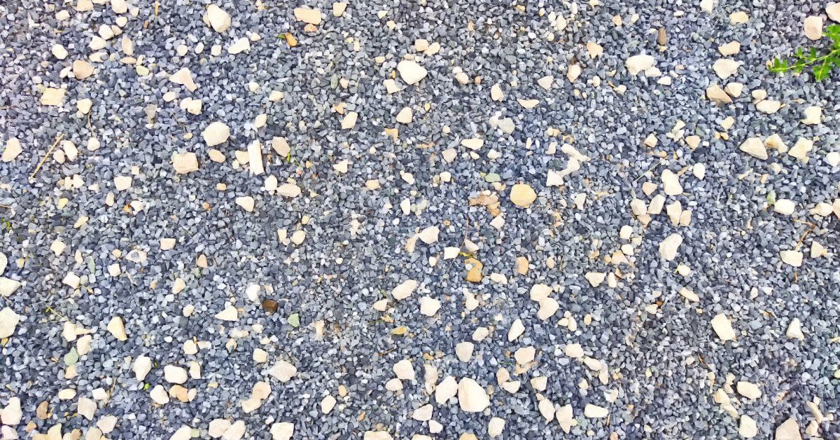 A plot of ground covered by a patch of textured gravel and small stones, creating a firm base for paving.