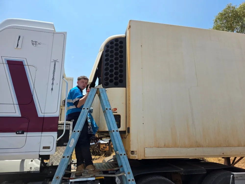 Man on a Ladder Inspecting a Refrigerated Truck Unit — BNS Refrigeration Services in Healy, QLD