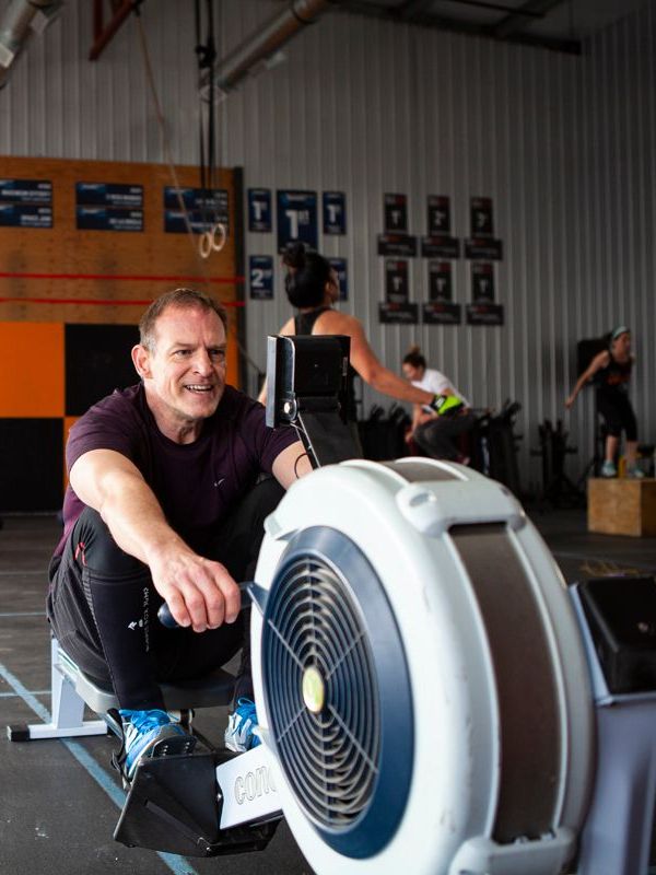 A man is sitting on a rowing machine in a gym