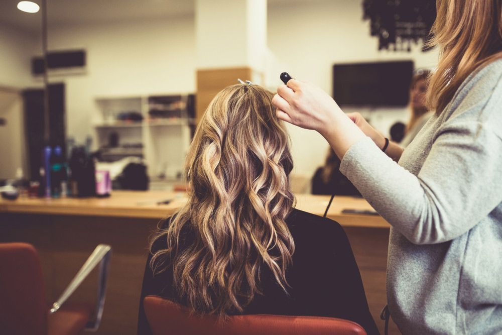 A Woman is Getting Her Hair Done by a Hairdresser in a Salon — Sophisticut Hair Salon in Mysterton, QLD