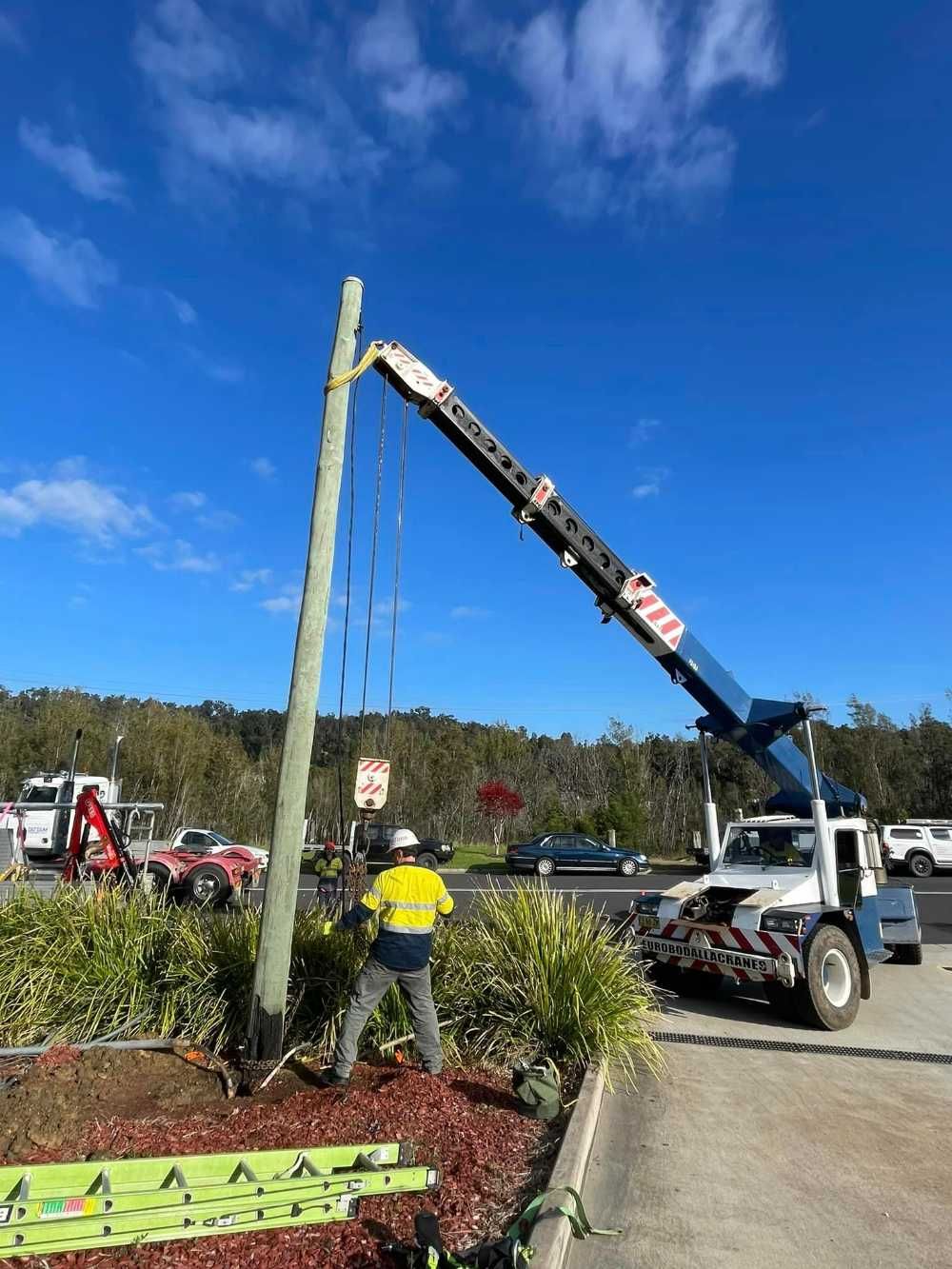 A Crane Is Lifting A Pole In A Parking Lot — BayCoast Electrical & Control Solutions in Sussex Inlet, NSW