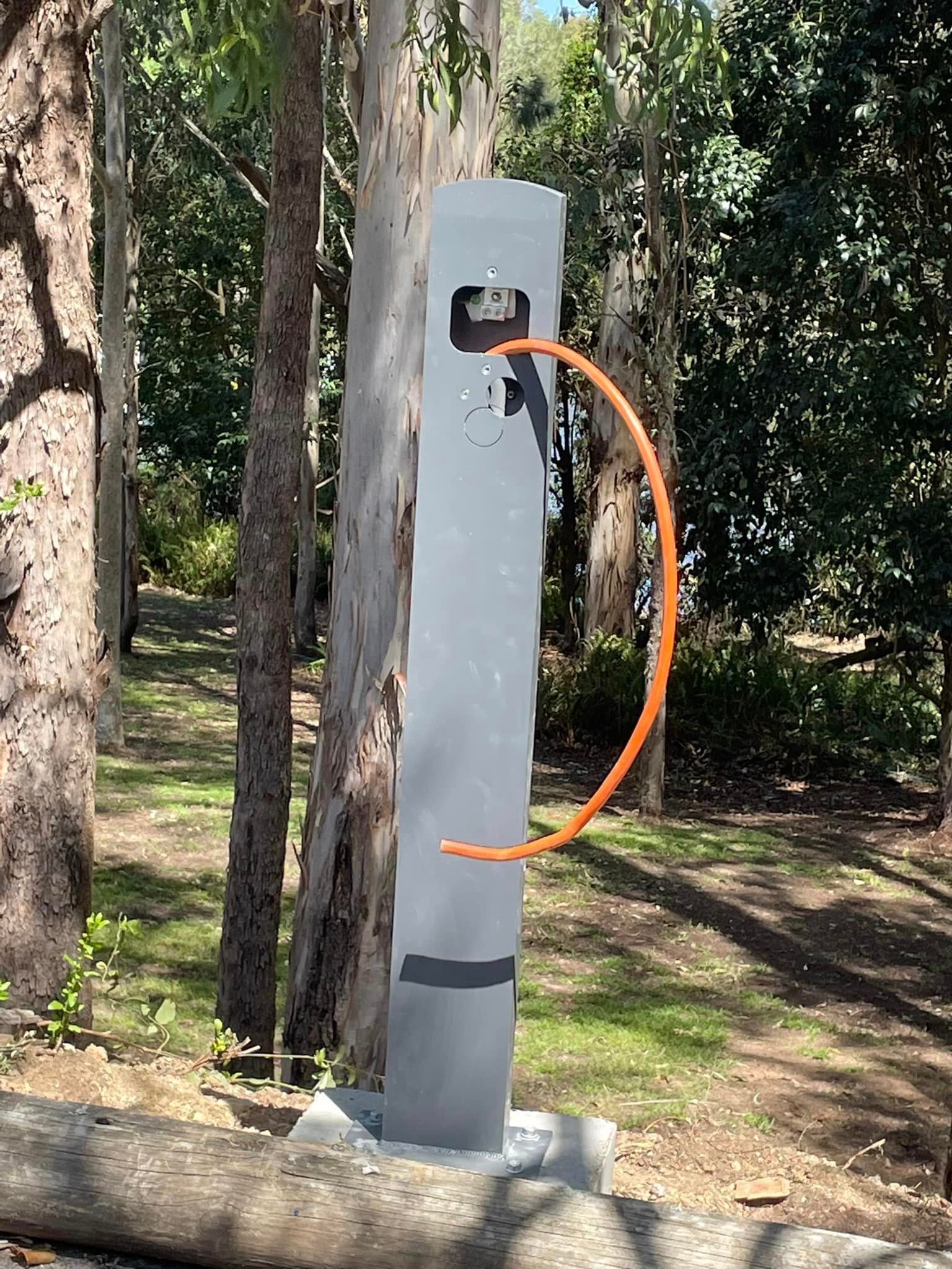 A Woman Is Charging Her Electric Car In A Garage — BayCoast Electrical & Control Solutions in Maloneys Beach, NSW