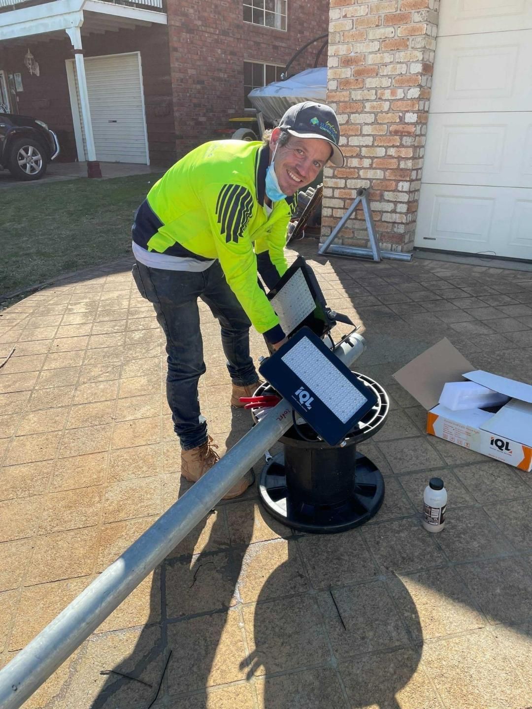 A Man Is Installing A Street Light On A Pole — BayCoast Electrical & Control Solutions in Ulladulla, NSW