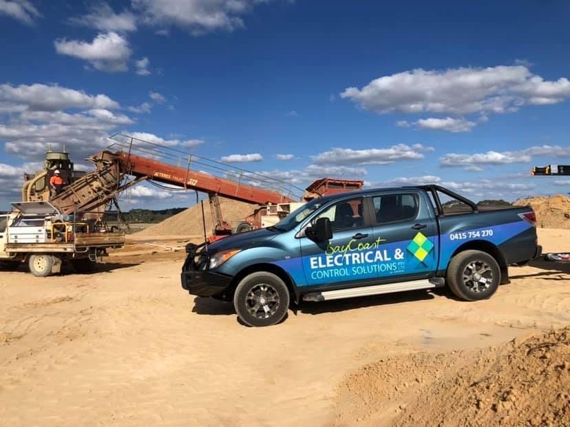 An Electrical Truck Is Parked In A Dirt Field — BayCoast Electrical & Control Solutions in Maloneys Beach, NSW