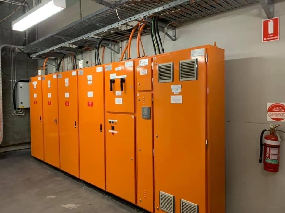 A Row Of Orange Electrical Boxes In A Room With A Fire Extinguisher — BayCoast Electrical & Control Solutions in Maloneys Beach, NSW