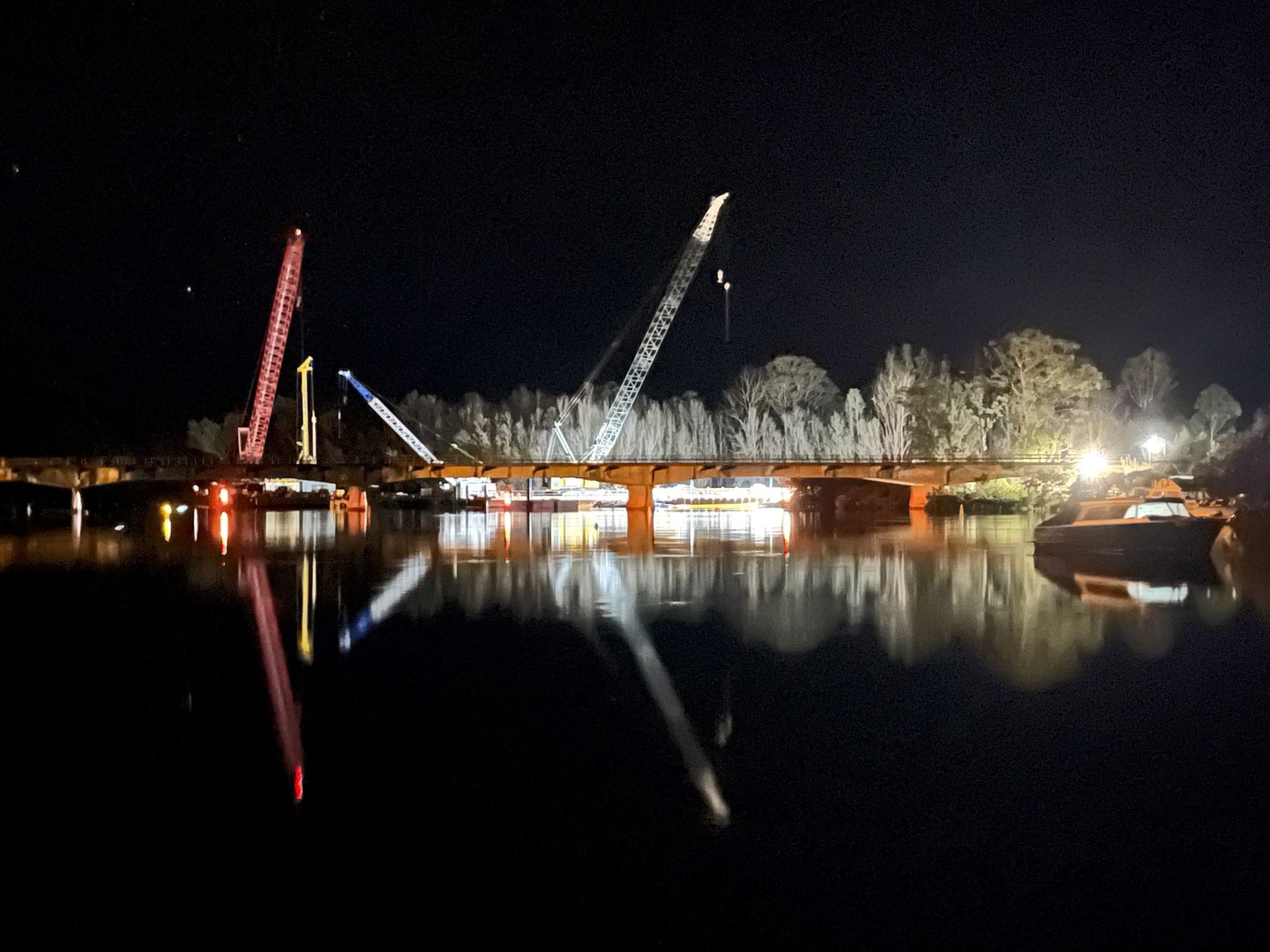 A Bridge Is Being Built Over A Body Of Water At Night — BayCoast Electrical & Control Solutions in Maloneys Beach, NSW