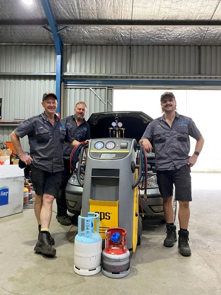 Three workers standing beside a yellow industrial machine with gas cylinders in a workshop. — Maddock Motors-Wodonga Auto Air In Wodonga, VIC