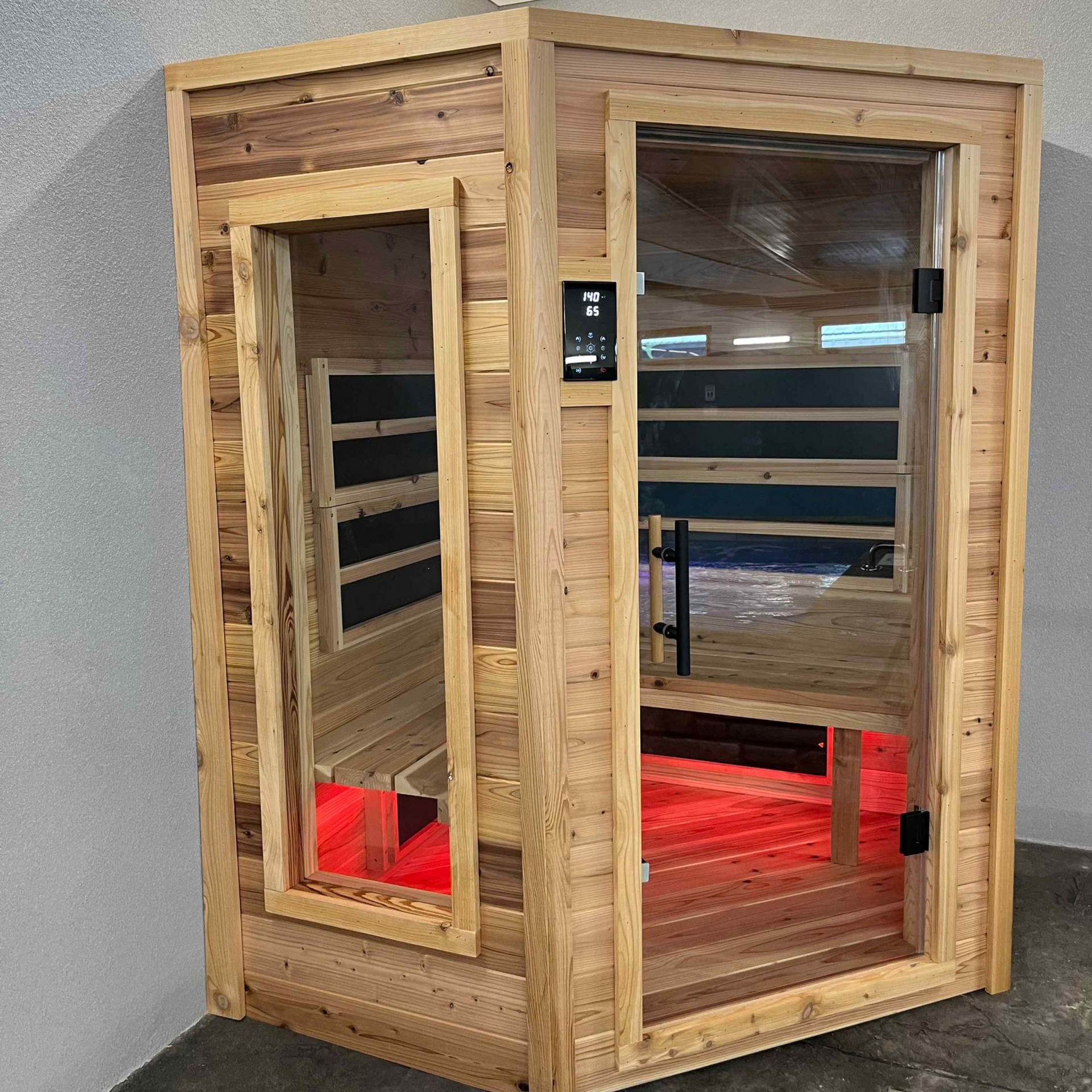 Wooden infrared sauna with glass door and red interior lighting.