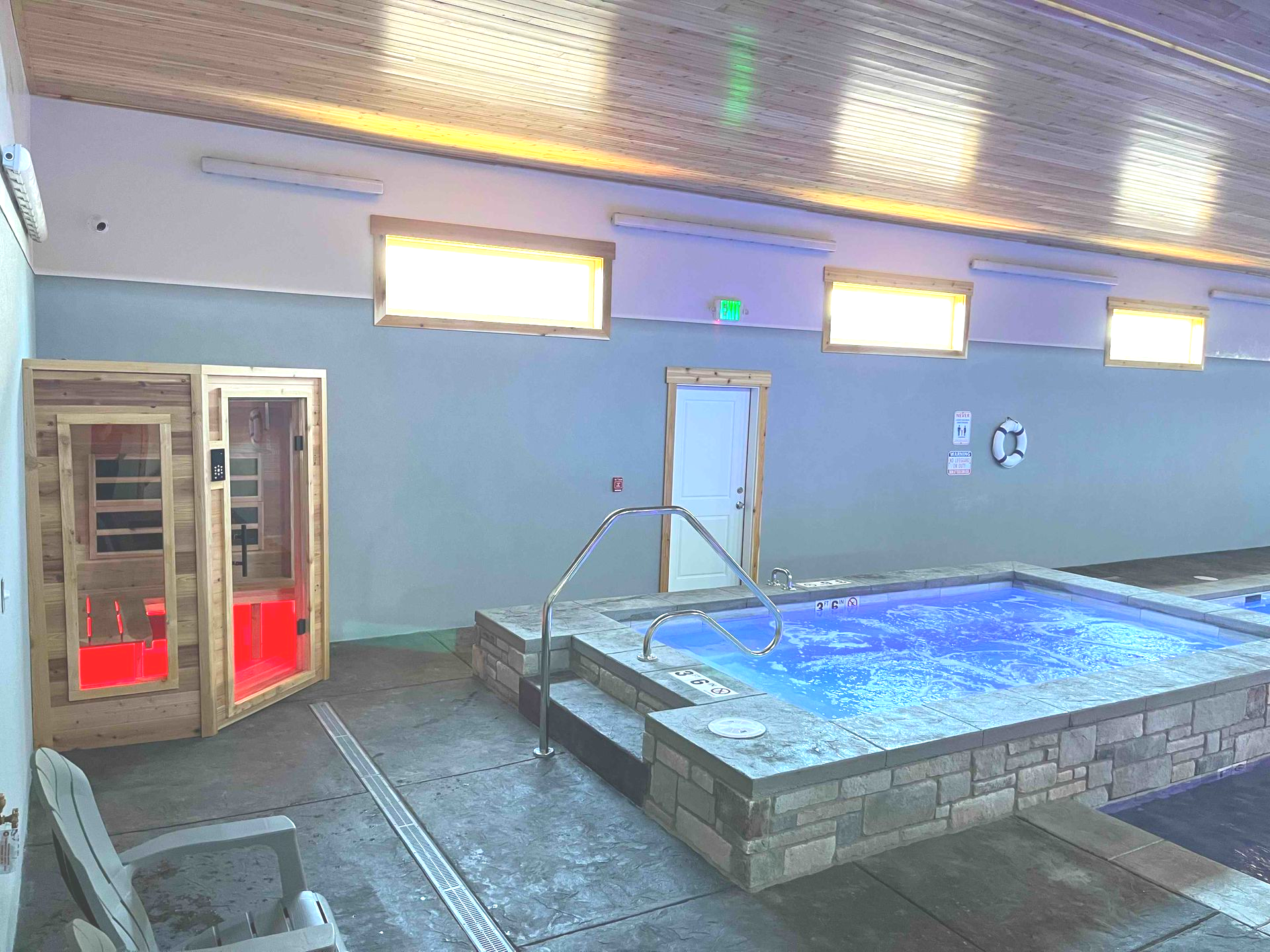 Indoor spa area with a sauna, hot tub, and doorway.