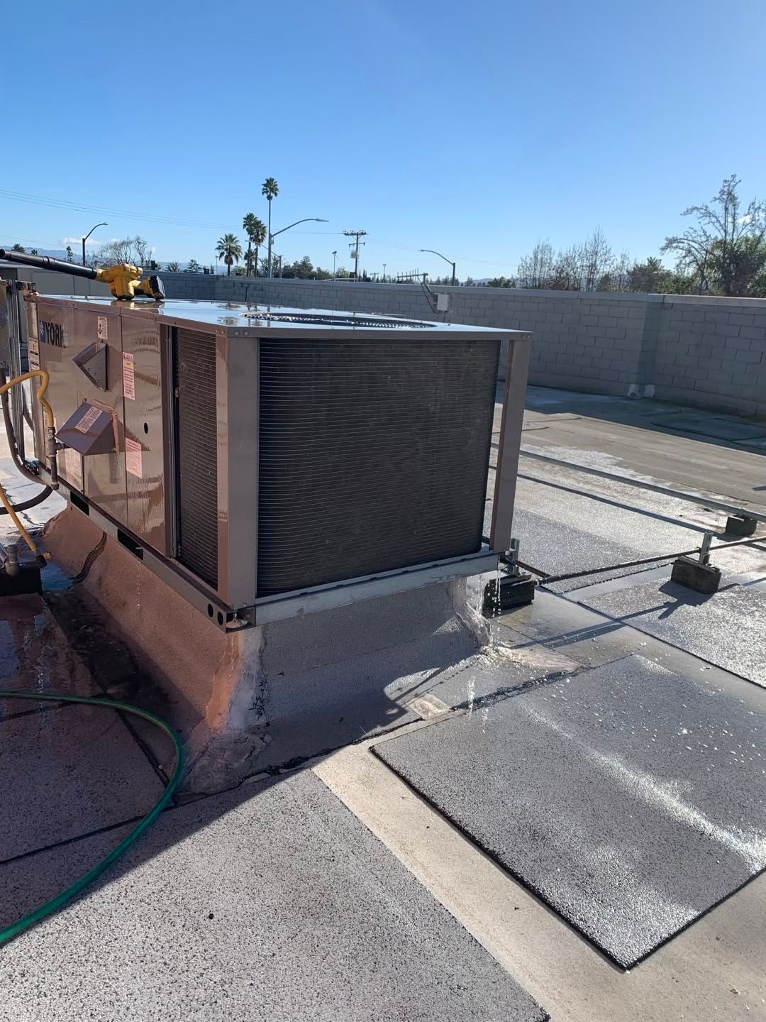 Rust-colored rooftop HVAC unit with a large fan grille on a flat roof under a clear sky.