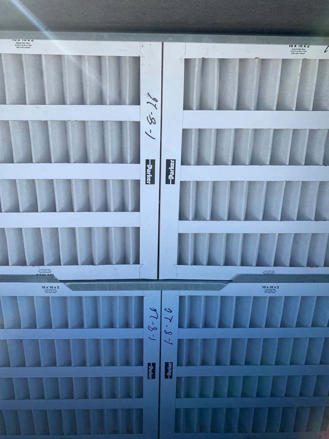White louvered vent or filter panels stacked in rows on a wall, with a blue-tinted lower section.