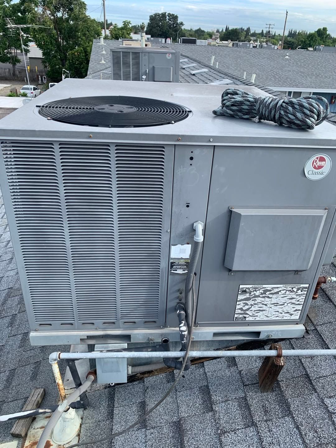 Large rooftop HVAC unit with fan vents and metal piping on a gravel roof