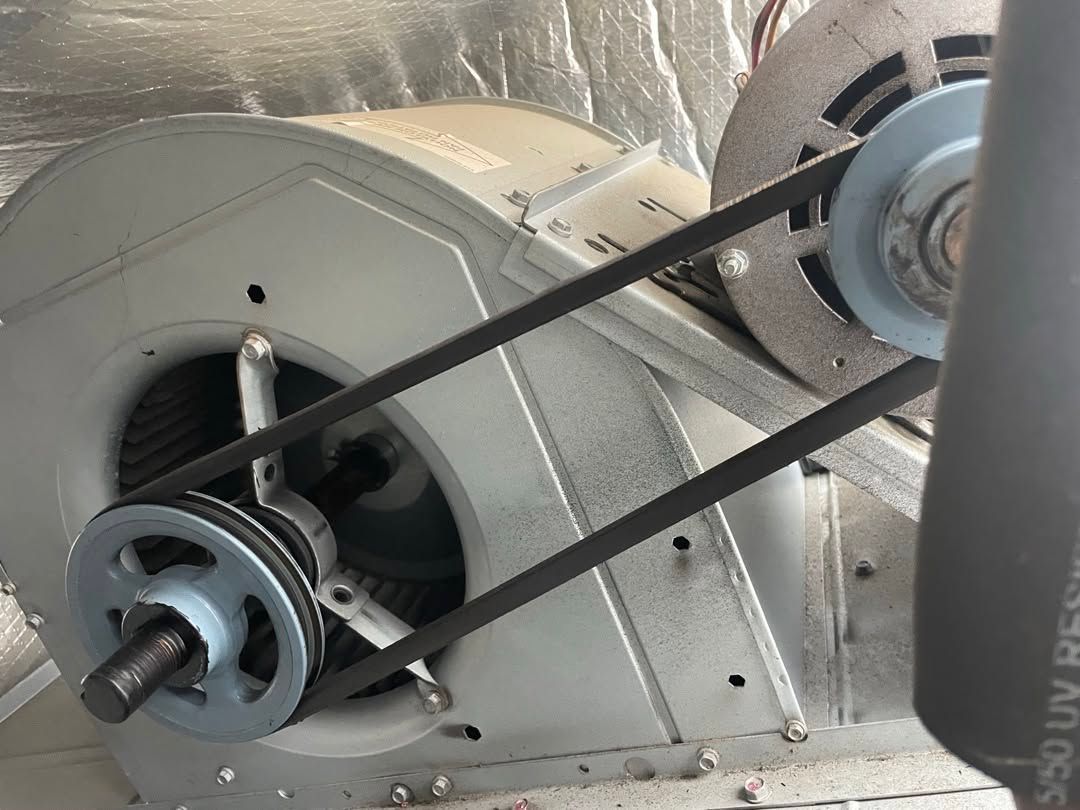Industrial blower motor with twin drive belts and pulleys inside a metal housing