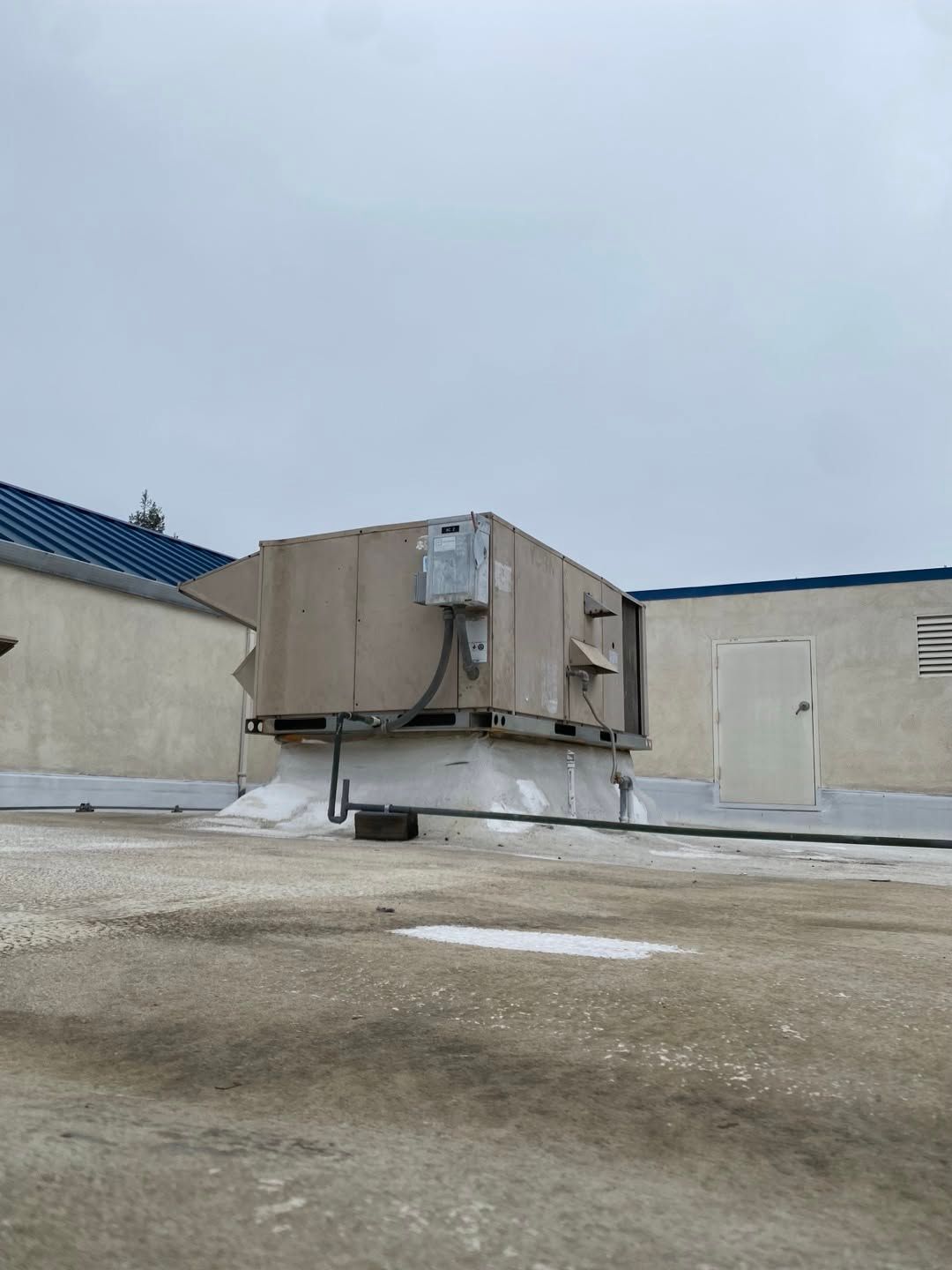 Industrial rooftop HVAC unit on a flat roof under an overcast sky
